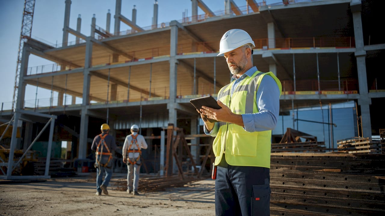 Construction safety supervisor checking digital tablet outdoors